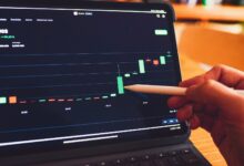 a person is holding a pencil in front of a laptop